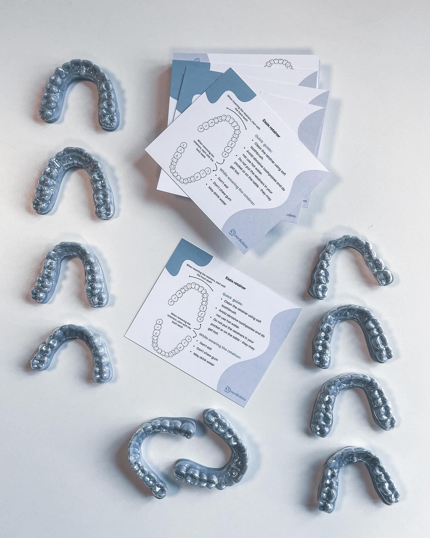 Multiple Essix retainers with NordicDens patient instruction cards