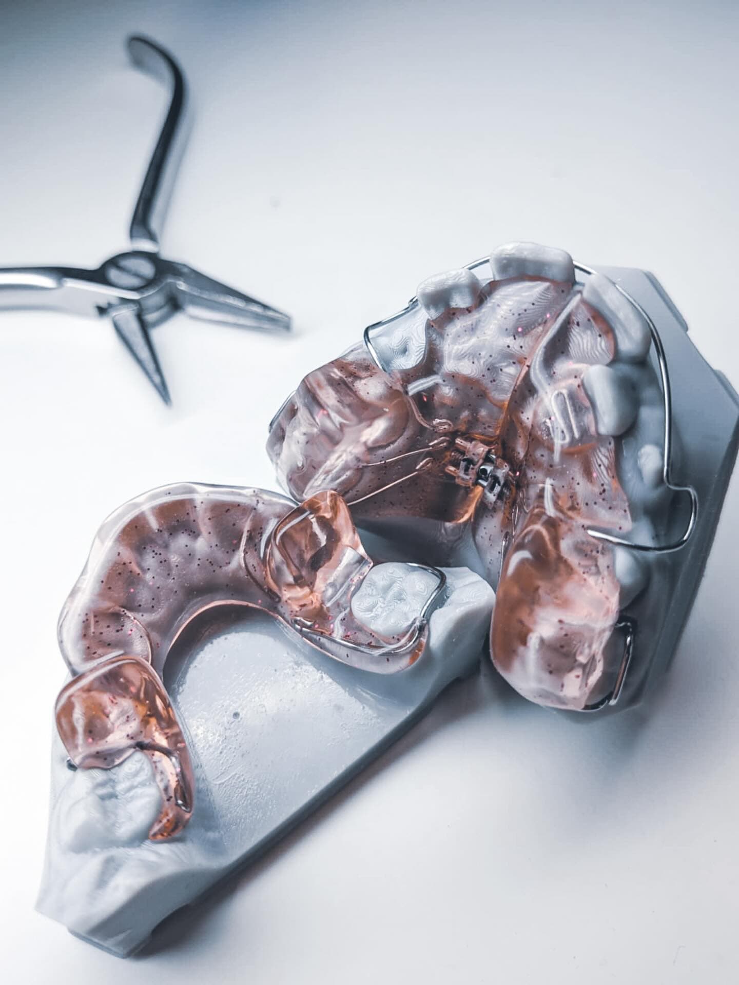 Orthodontic removable appliance with acrylic and wire work alongside dental pliers